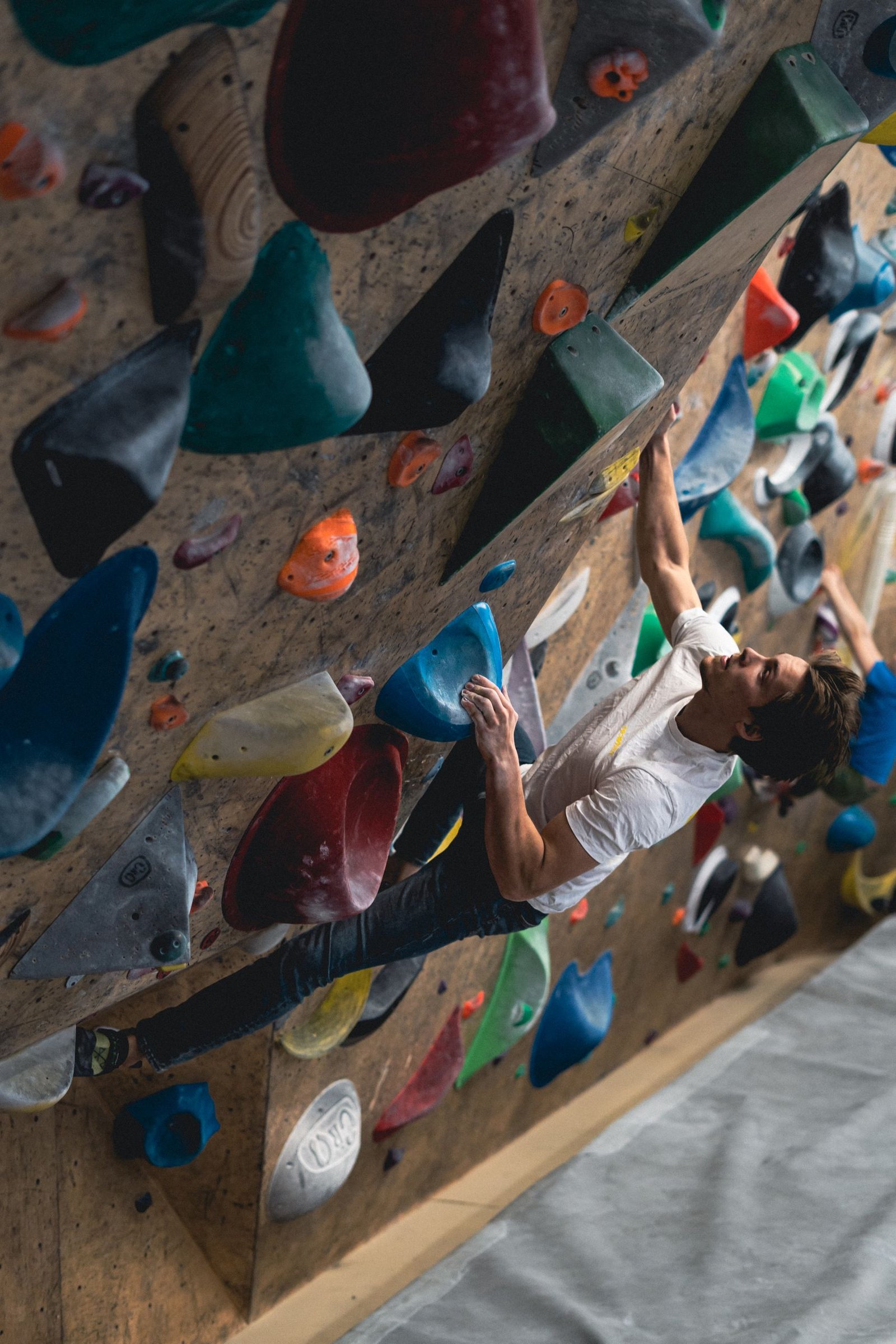 A young man engages in a challenging bouldering activity on a vibrant indoor climbing wall.